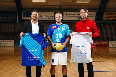 Stadtmarketing Dessau-Roßlau kooperiert mit Handball-Bundesligisten - v.l.: DRHV-Geschäftsführer Sebastian Glock, Handballer Vincent Sohmann und Stadtmarketing-Geschäftsführer Hannes Wolf präsentieren die Rückseite des Trikots - Foto: Sebastian Köhler